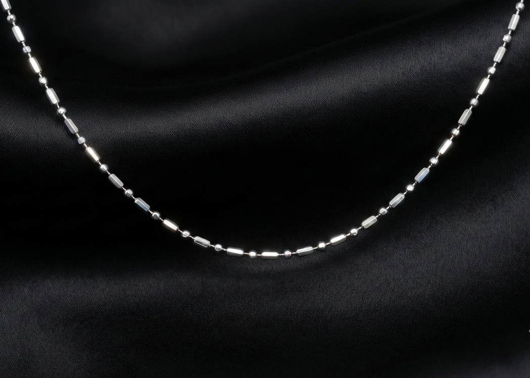 Silver chain necklace on a dark fabric background