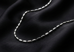 Silver chain necklace on black fabric