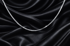 Silver chain on black satin fabric