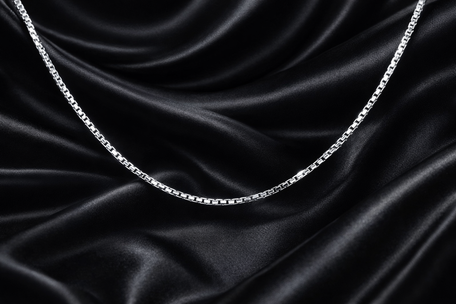 Silver chain on black satin fabric
