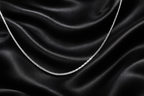 Silver chain on black satin fabric