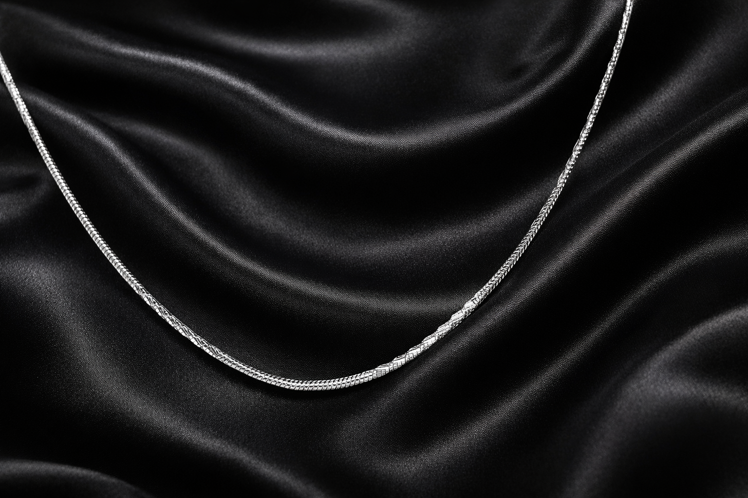 Silver chain on black satin fabric
