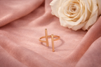 Rose gold ring on a pink fabric background with a white rose.