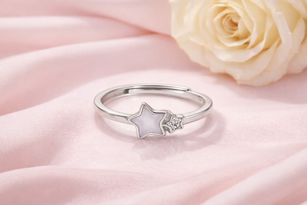 Silver ring with star design on pink fabric with a rose