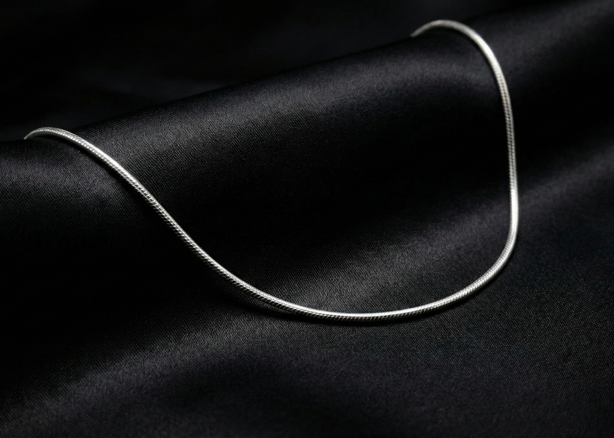 Silver necklace on a black fabric background