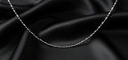 Silver chain necklace on black satin fabric