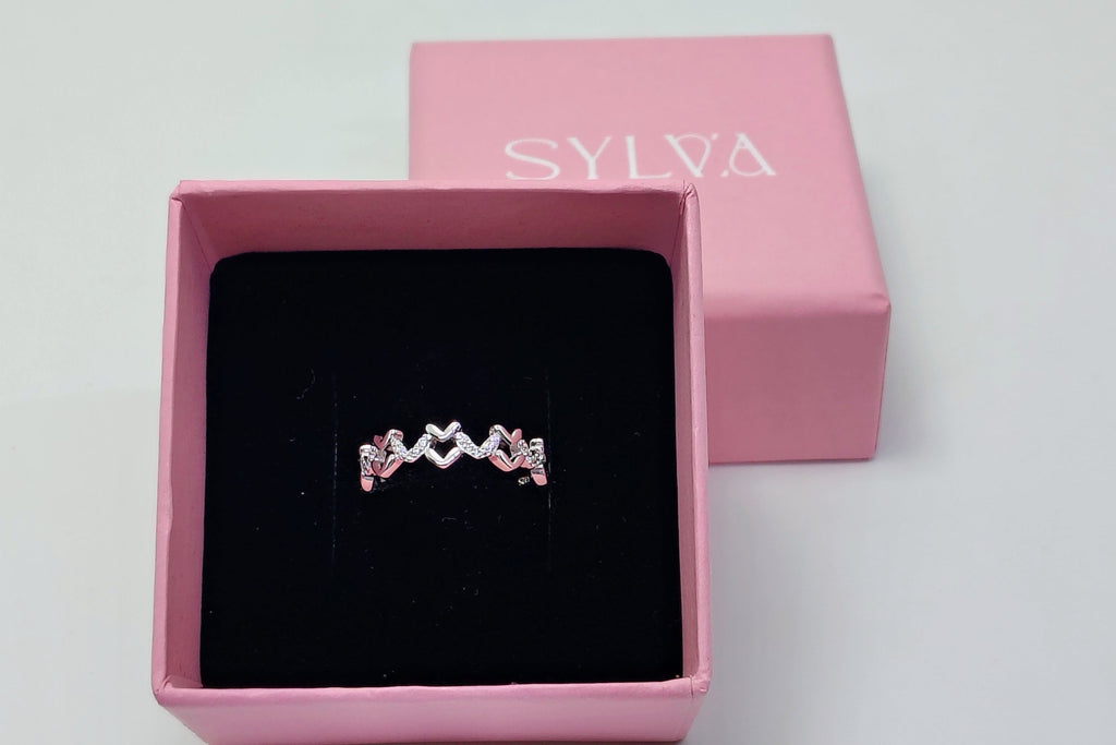 Silver ring in a pink box with 'SYLVIA' branding on a white background