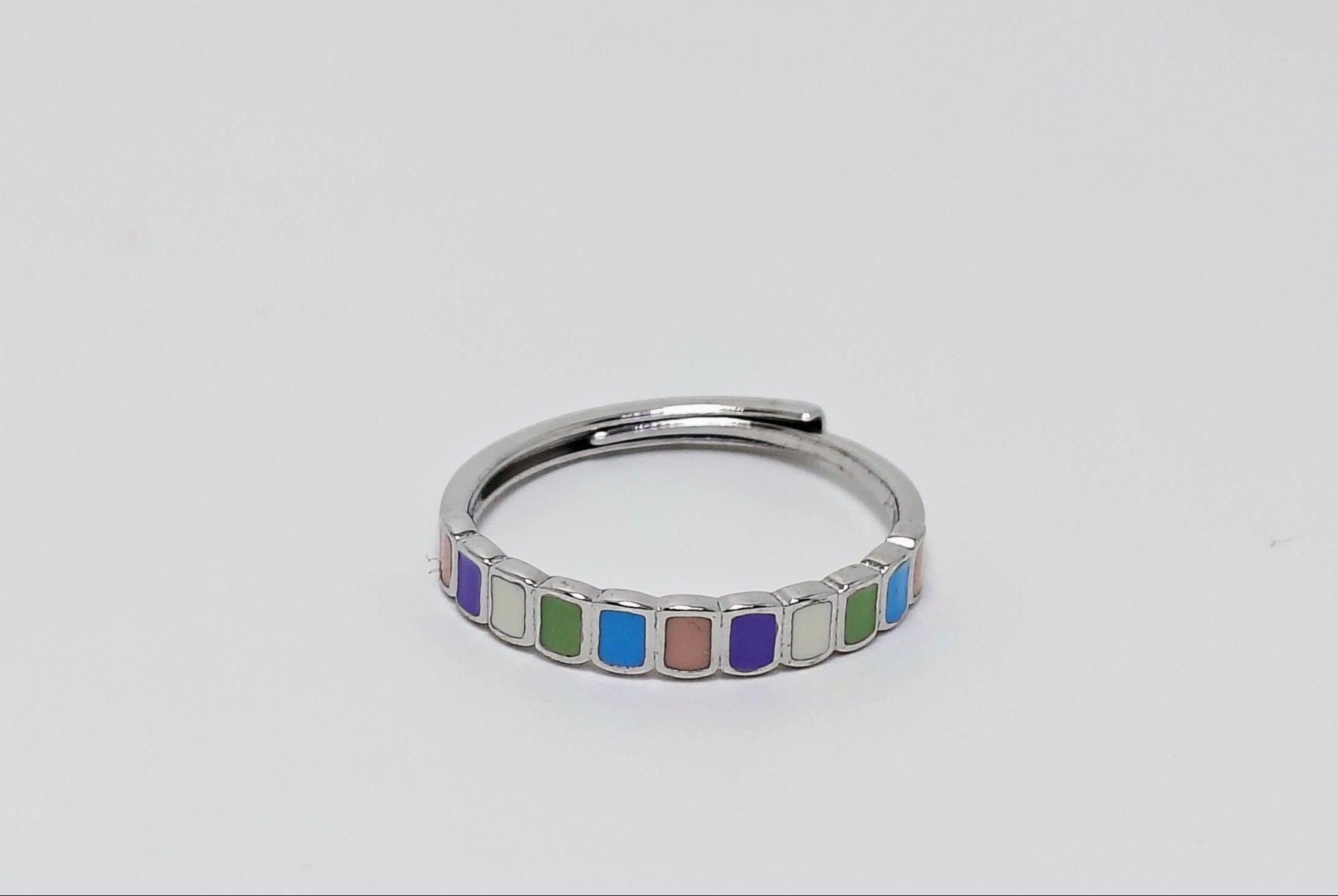 Silver ring with colorful square stones on a light gray background