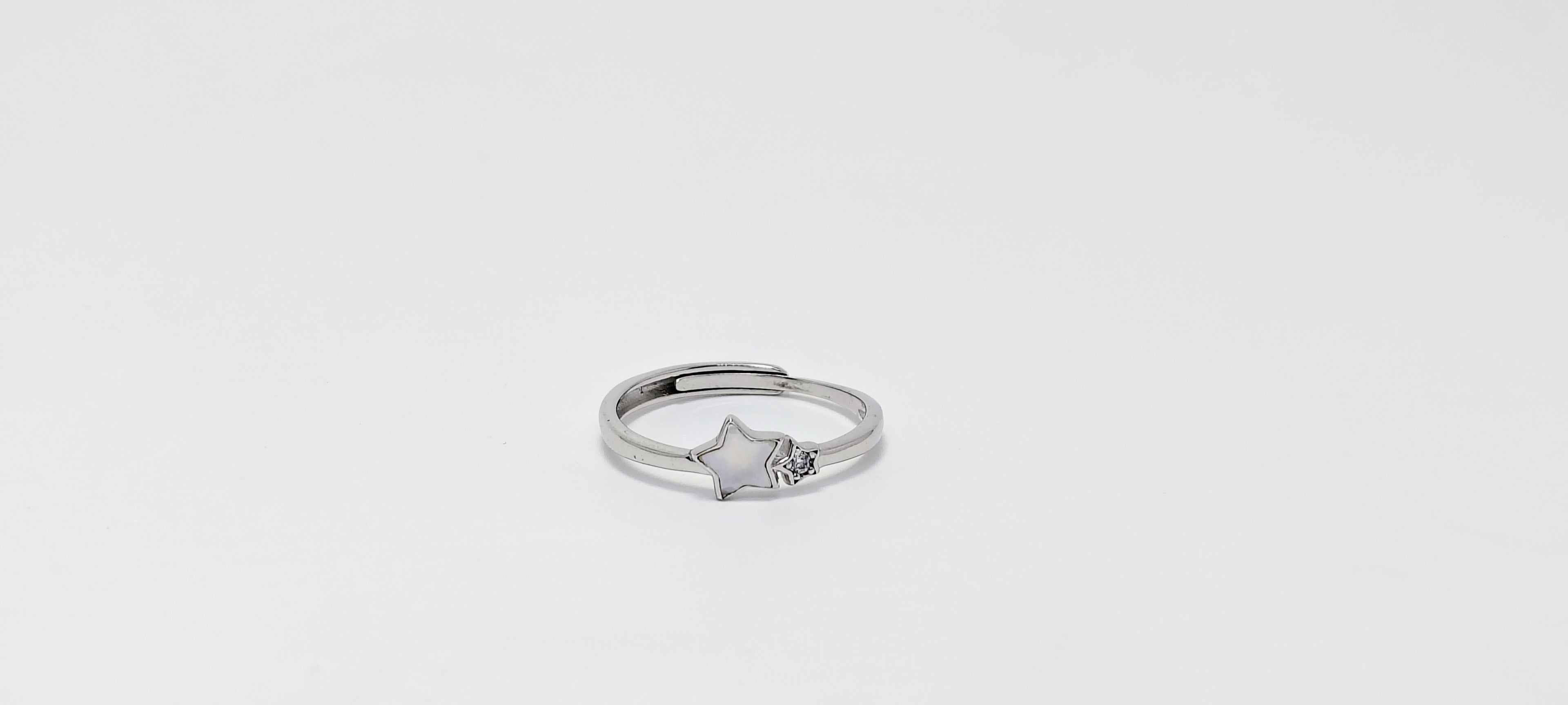 Silver ring with a star design on a light gray background