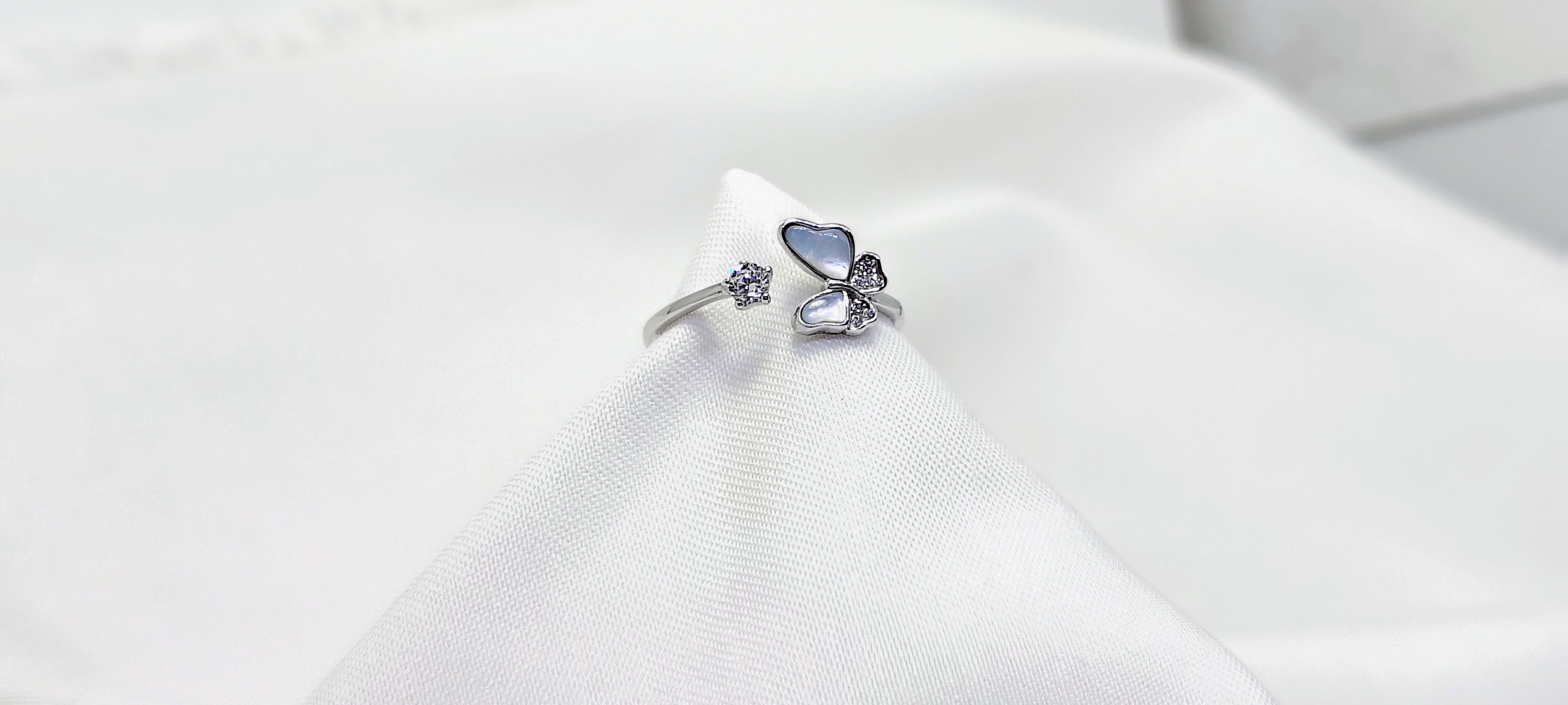 Silver ring with blue gemstone on a white cushion