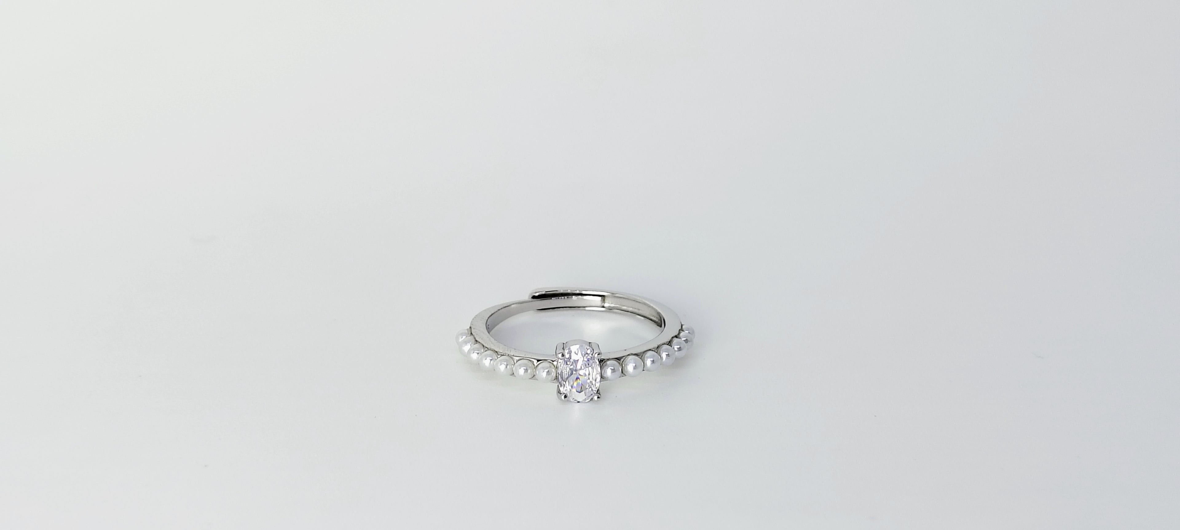 Silver ring with a diamond on a light gray background