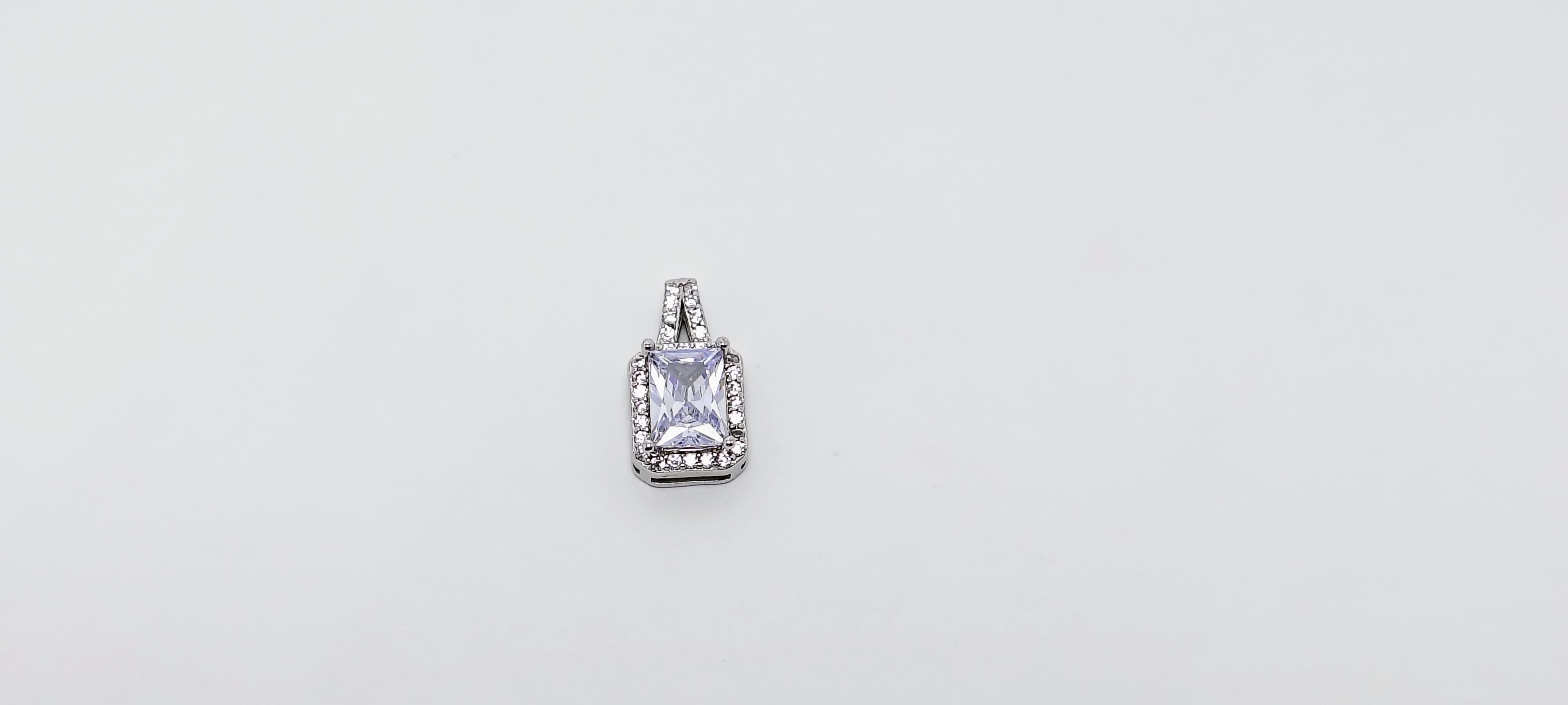 Silver pendant with a clear gemstone on a light gray background