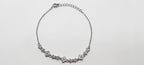 Silver necklace with floral designs on a light gray background