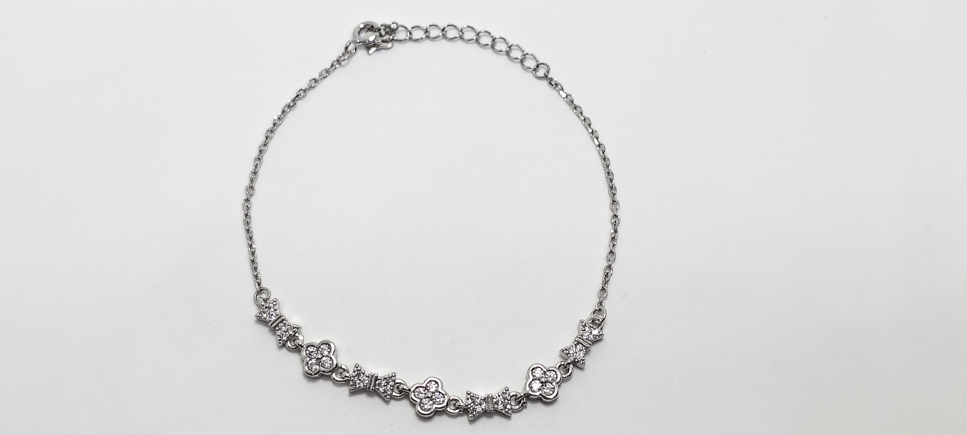 Silver necklace with floral designs on a light gray background