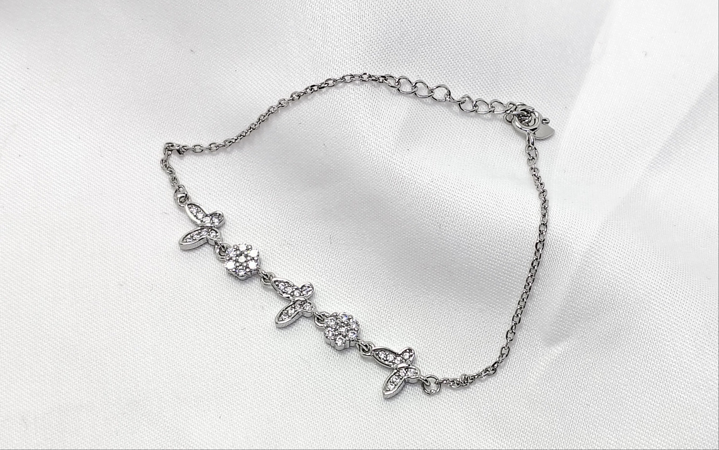 Silver bracelet with floral design on a white background