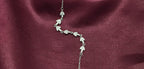 Silver necklace with leaf designs on a burgundy fabric background