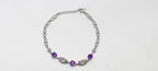 Silver necklace with purple gemstones on a white background