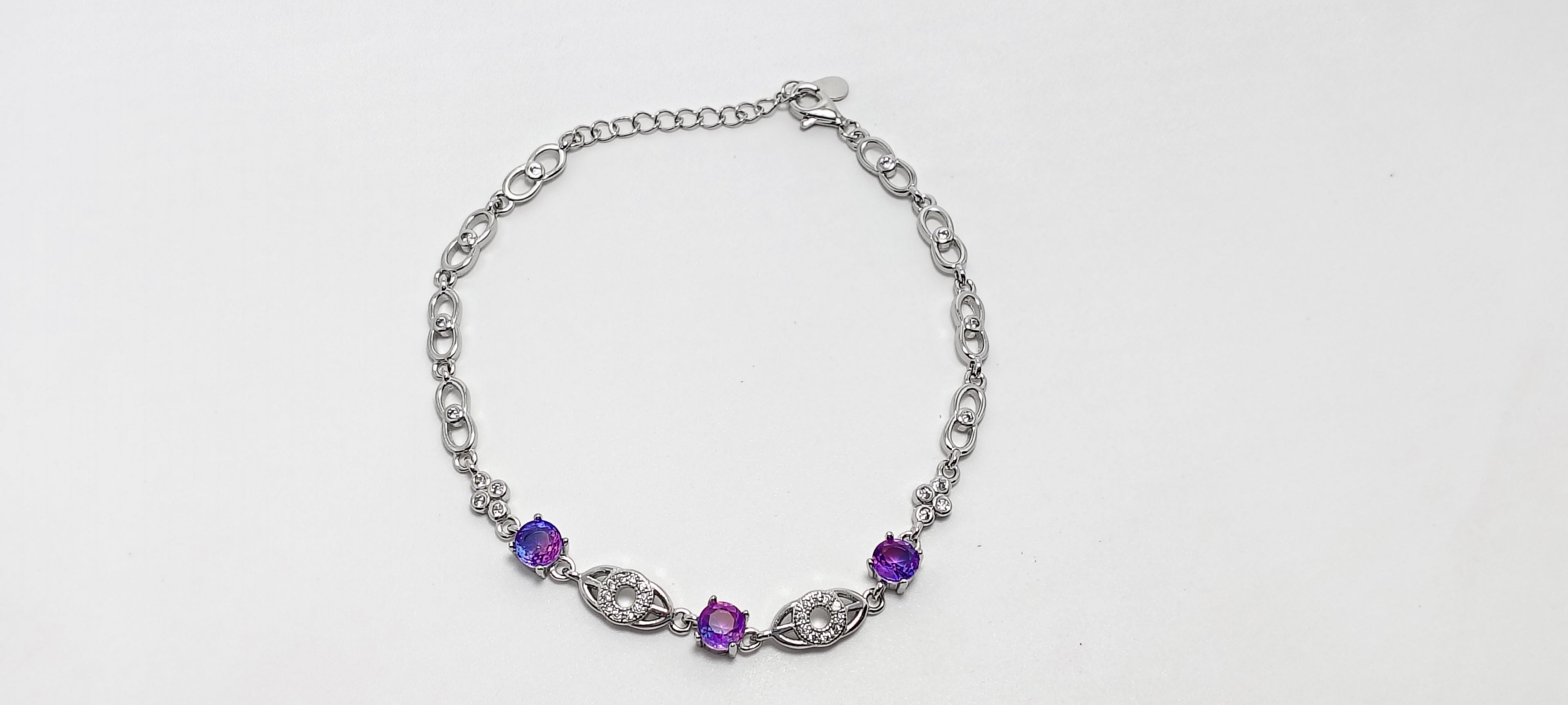 Silver necklace with purple gemstones on a white background