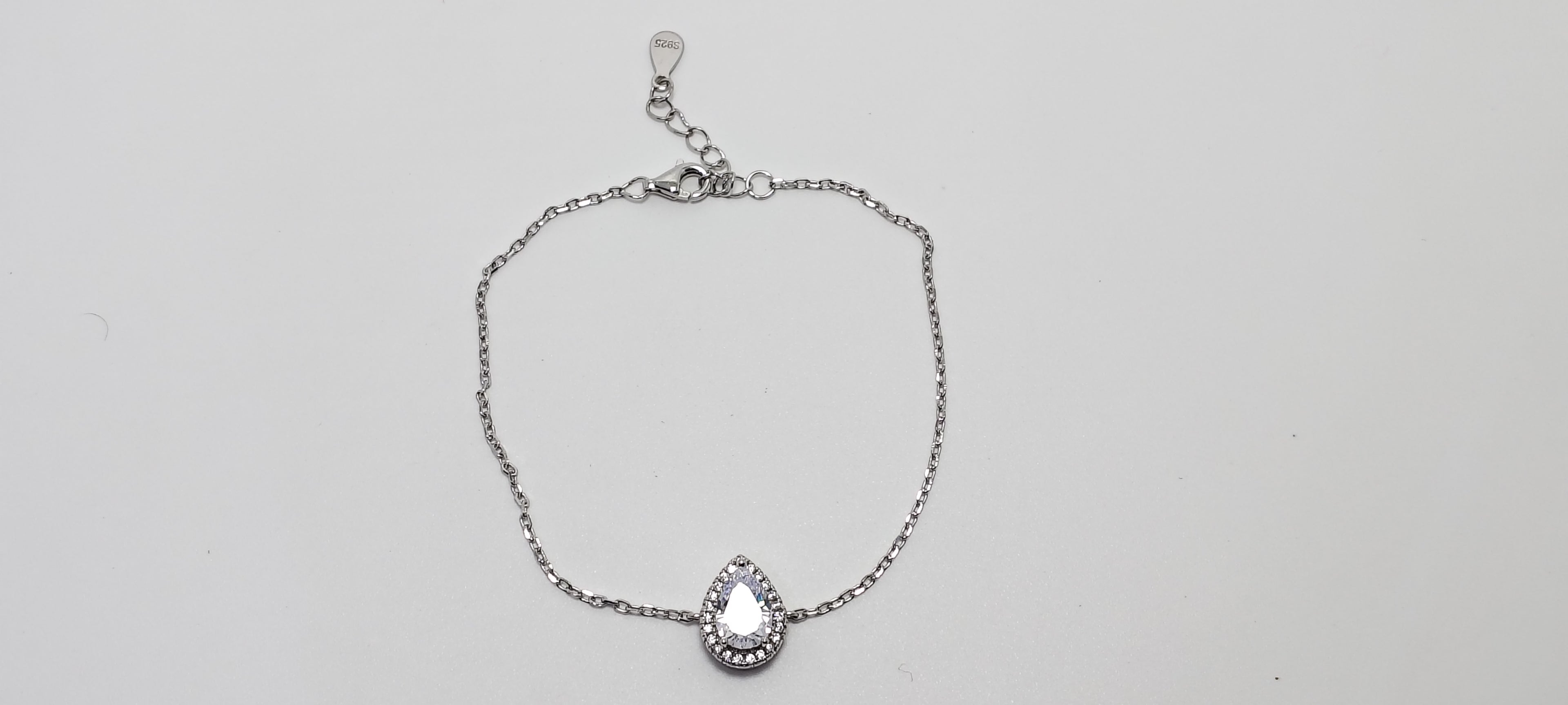 Silver bracelet with a teardrop-shaped charm on a light gray background