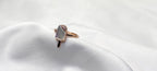 Rose gold ring with a gemstone on a white satin surface