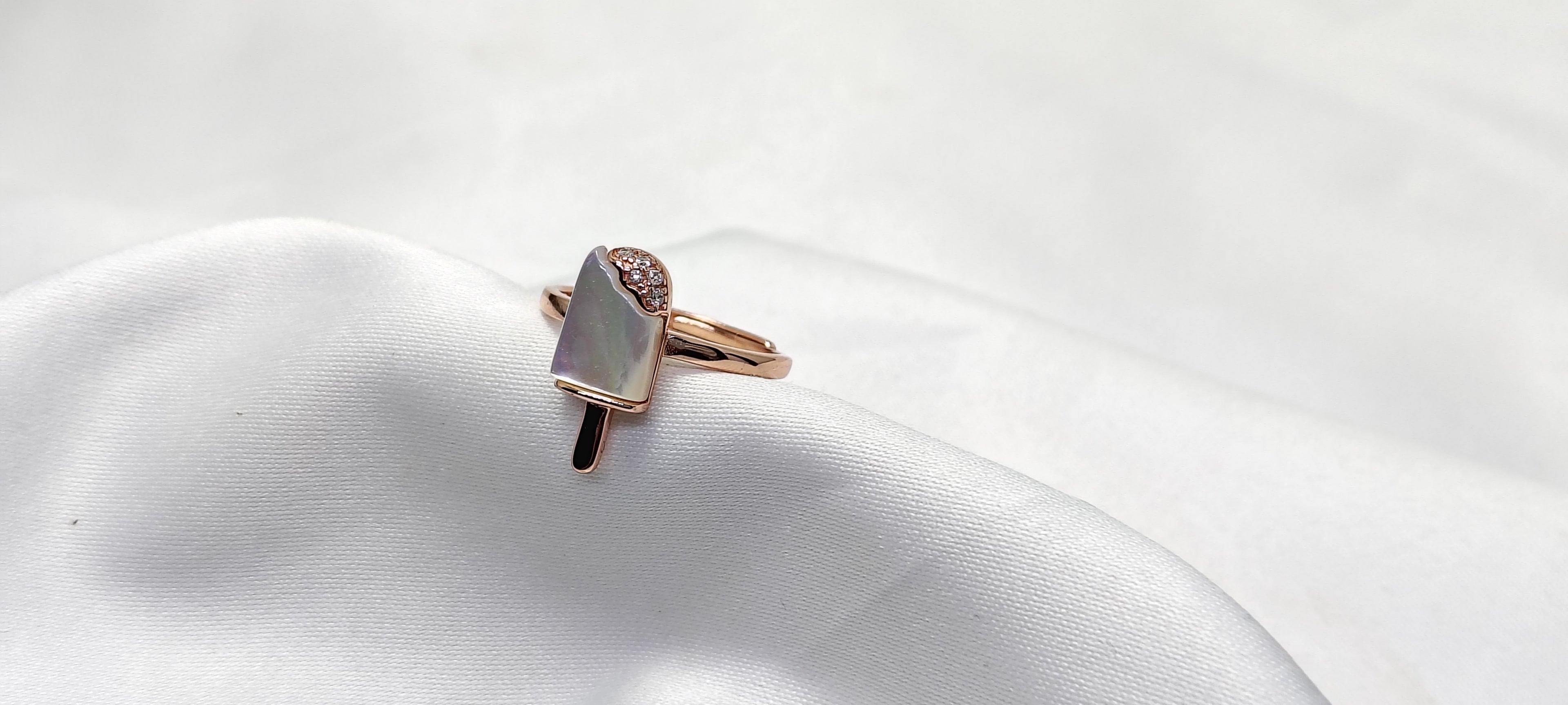 Rose gold ring with a gemstone on a white satin surface