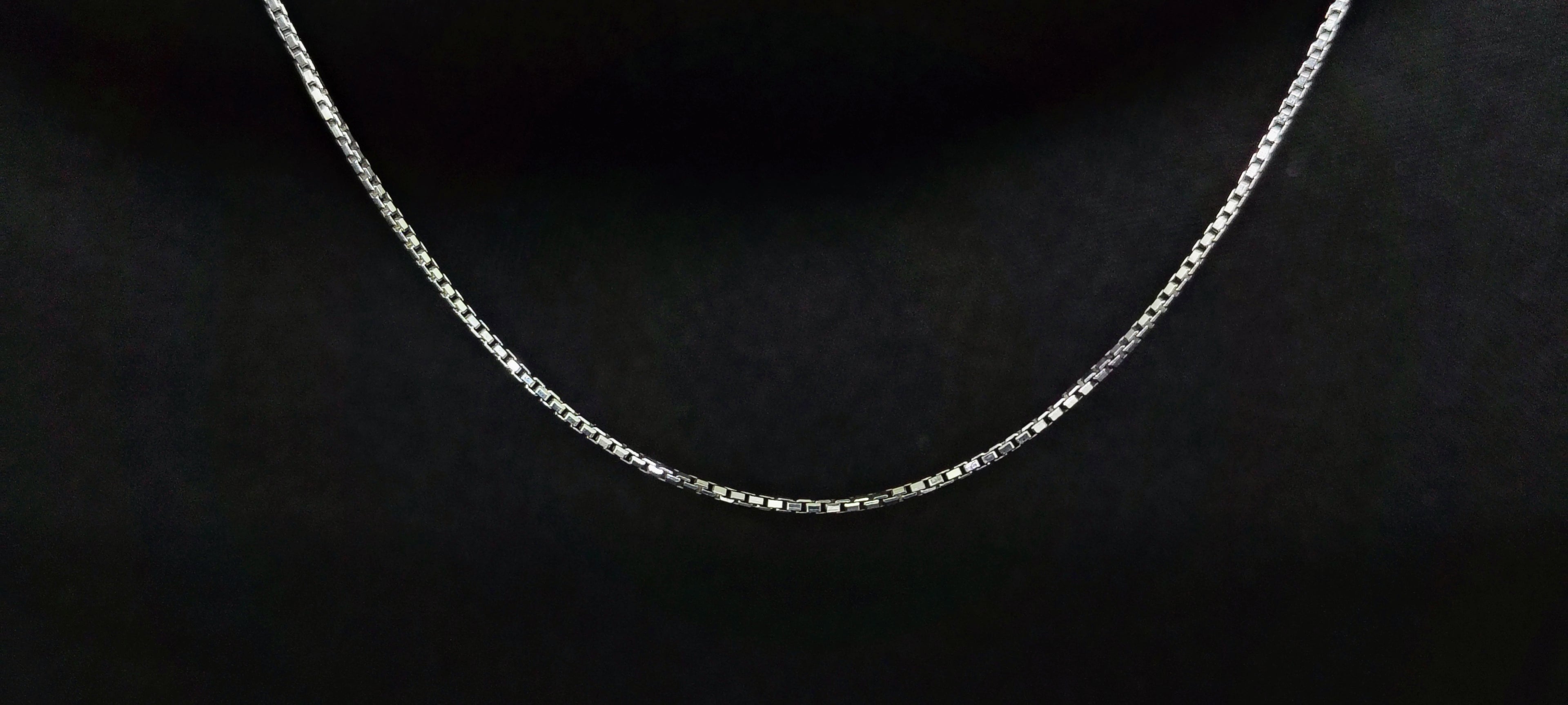 Silver chain necklace on a black textured background